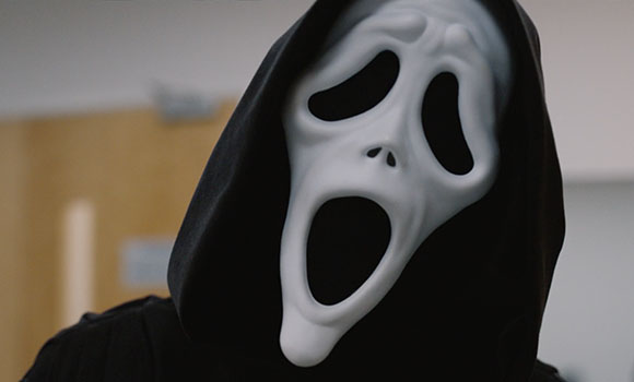 A person wearing a white screaming mask and a black hooded cloak.