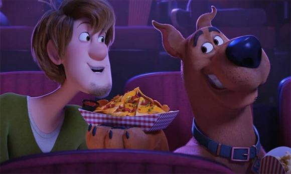 Animated Shaggy and Scooby-Doo smiling while looking at a tray of nachos in a dark theater.