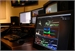 Several computer monitors displaying various data and interfaces on a dark desk.