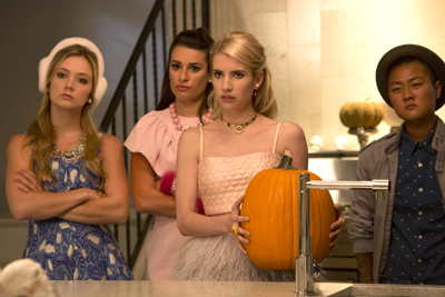 Four young people stand in a kitchen, looking towards the left with serious expressions.