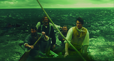 Four men in period clothing rowing a small wooden boat through dark, choppy ocean waves.