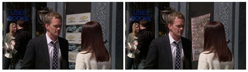 A man in a dark suit and a woman with long brown hair stand outdoors near a storefront.