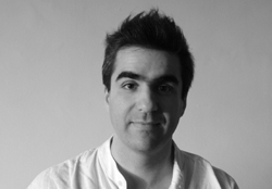 Black and white headshot of a man with dark hair and thick eyebrows looking at the camera.