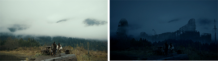 Two people walk through a foggy field toward a dark forest and mountains under a heavy mist.