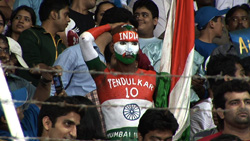 A fan with Indian flag face paint and a jersey reading 'TENDULKAR 10' in a crowd.