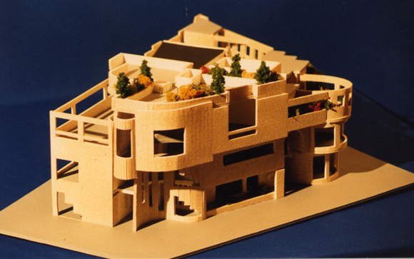 A light-colored architectural scale model of a complex, multi-level building with curved walls and rooftop greenery.