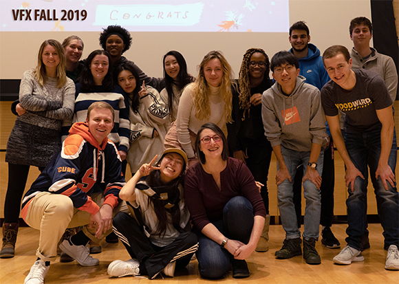 A diverse group of young adults smiling and posing together for a group photo indoors.