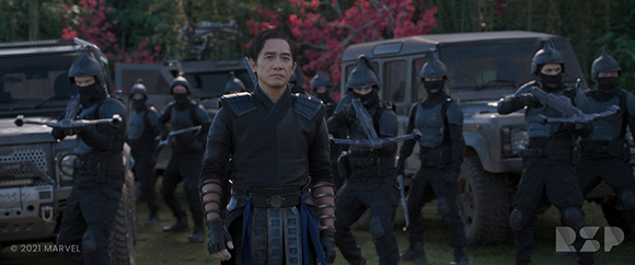 A man in dark martial arts attire stands in front of several soldiers in black tactical gear and helmets.