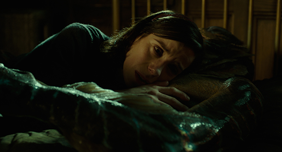 A person with dark hair lies down, looking upward with a pained or distressed facial expression.