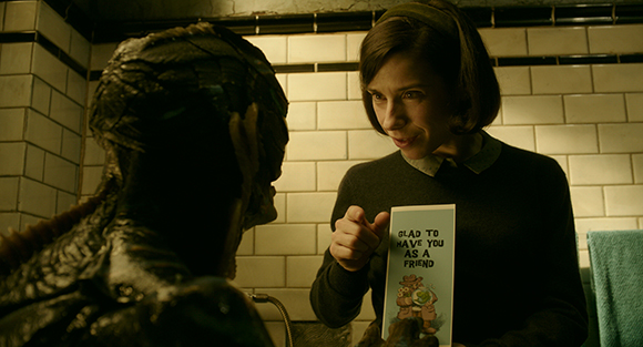 A woman in a dark sweater holds a card that reads 'Glad to have you as a friend' toward a person in a costume.