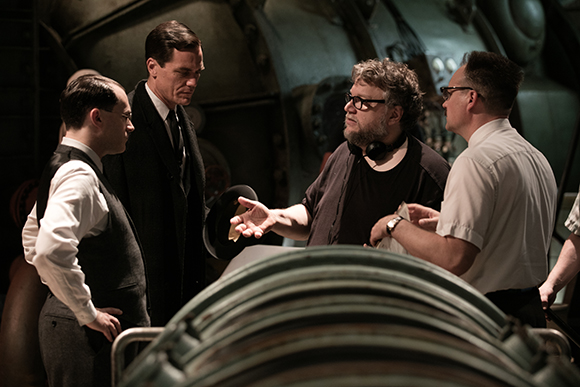 Four men stand in a dark industrial space, engaged in a serious discussion.