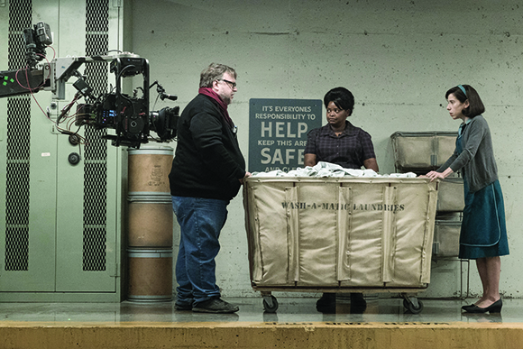A film crew stands around a large laundry cart on a movie set.