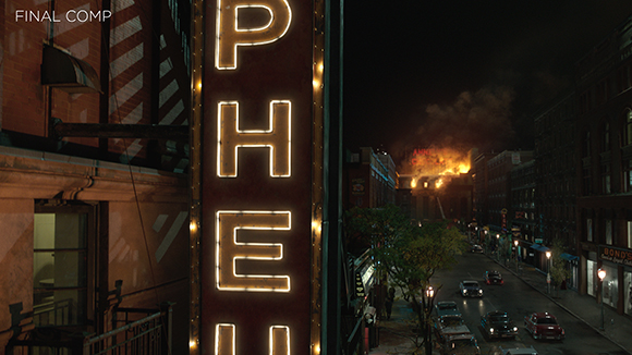 A glowing vertical sign stands beside a dark city street where a building is engulfed in flames and smoke.