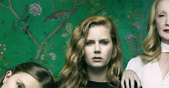 Three women with cracks running across their faces against a green floral patterned backdrop.