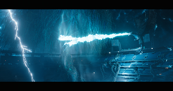 A dragon breathes a bright blue beam of energy toward a dark, metallic structure amidst blue lightning.