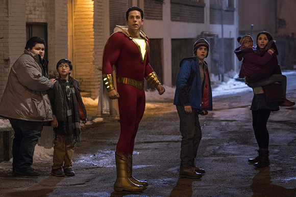 A man in a red and gold superhero costume stands in an alley with four children.