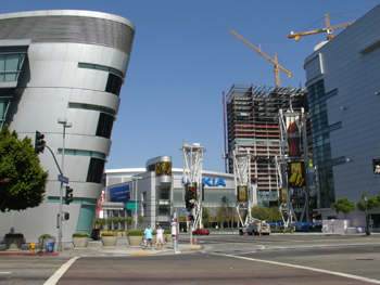 Modern buildings with unique architectural designs and construction cranes against a clear blue sky.