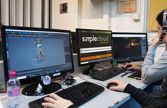 Two people using computer monitors displaying animation software and a website in an office setting.