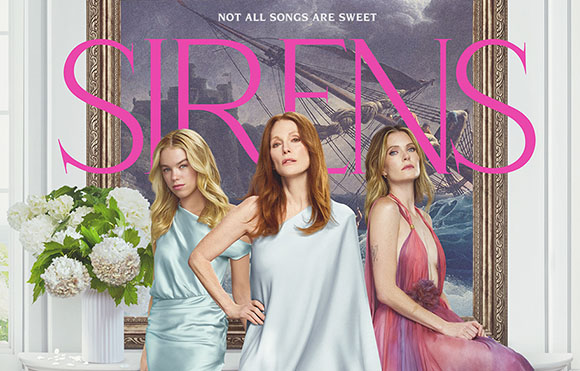 Three women in elegant dresses pose before a large painting titled SIRENS in pink lettering.