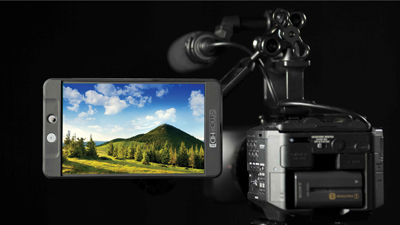 A smartphone displaying a landscape photo is mounted to a professional video camera rig against a black background.