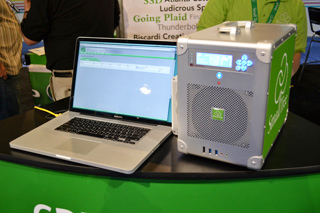 A silver laptop next to a large silver and green external storage device on a green counter.