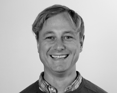 Black and white headshot of a smiling man wearing a collared shirt.