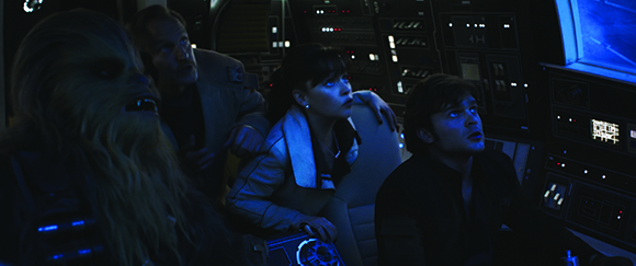 Four people with intense expressions look up inside a dark, high-tech spaceship cockpit.