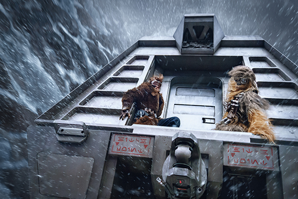 Two furry Wookiees sit in the open hatch of a gray spacecraft during a heavy snowstorm.