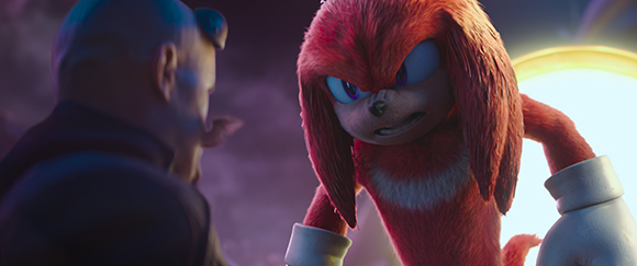 An anthropomorphic red echidna with an angry expression stares intensely at a man in profile.