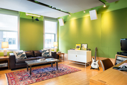 A living room with lime green walls, a dark leather sofa, a coffee table, and a patterned rug.