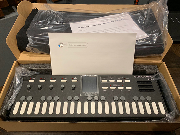 An unboxed black electronic MIDI controller with white keys and several control knobs and buttons.