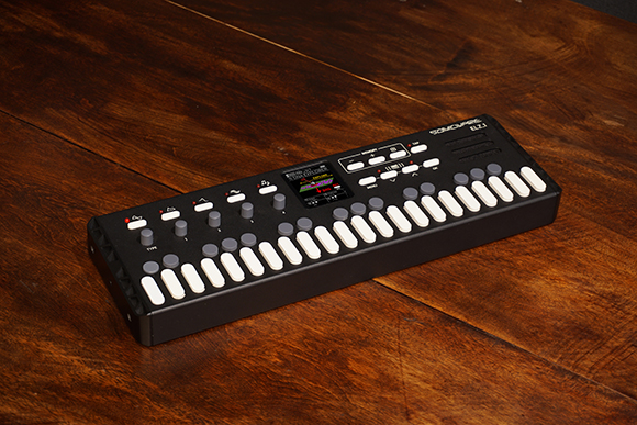 A black Sommoare ELT-1 electronic musical keyboard with white keys on a dark wooden table.