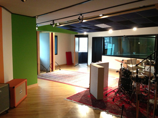A music rehearsal studio with a drum kit, amplifiers, and soundproofing panels on the walls.