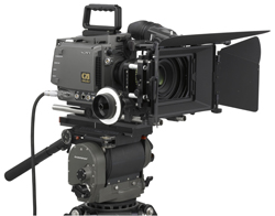 A professional black cinema camera with a large lens and matte box mounted on a heavy-duty tripod.