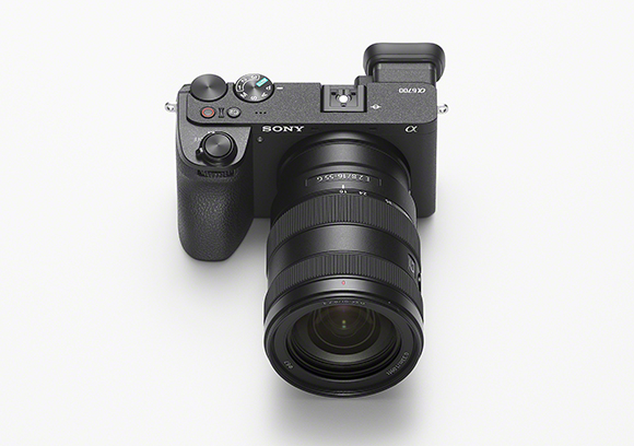 A black Sony mirrorless camera with a large attached zoom lens positioned against a white background.
