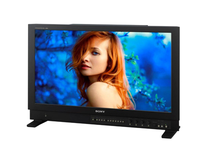 A professional Sony monitor displays a portrait of a woman with red hair against a blue, leafy background.