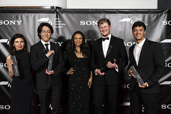 Five people in formal attire pose together holding awards in front of a black Sony backdrop.