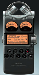 A black Sony PCM-D1 portable digital audio recorder with two microphones and orange analog level meters.