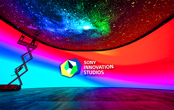 A studio interior with a starry galaxy ceiling, colorful curved walls, and a scissor lift on the left.