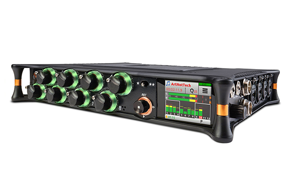 A black audio interface featuring green-rimmed control knobs and a small digital screen showing audio levels.