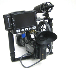 Video camera mounted with a large shotgun microphone and a digital audio recorder.