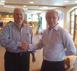 Two men in button-down shirts shaking hands indoors.