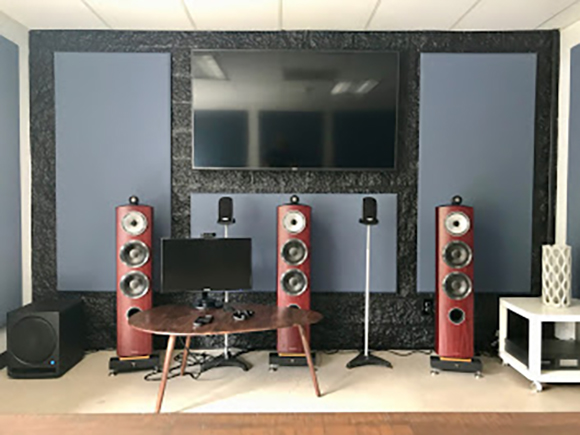A home theater room with three tall red floor-standing speakers, a large TV, and blue acoustic wall panels.