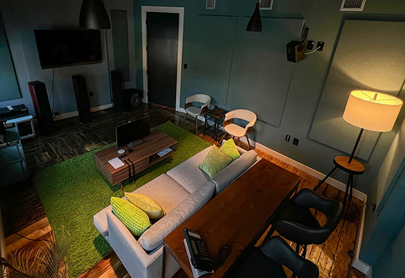 A living room featuring a light gray sofa, wooden coffee table, two white chairs, and a floor lamp.