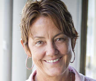 A smiling woman with short brown hair and large hoop earrings.