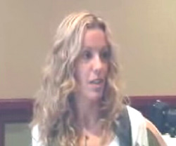A woman with long, wavy blonde hair looking slightly to her right.