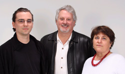 A man in a black shirt, a man in a leather jacket, and a woman in a white shirt with a red necklace.