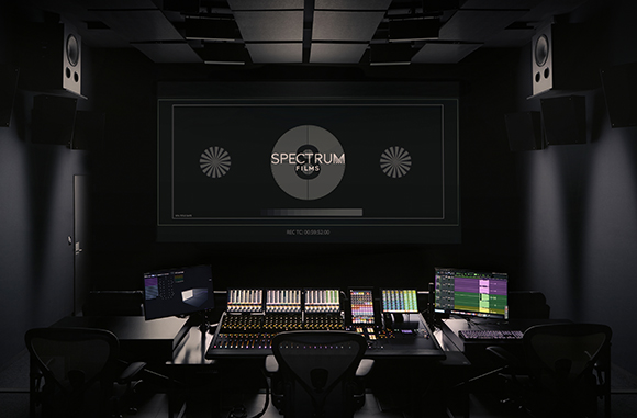 A dark film editing suite featuring a large projection screen and a large audio mixing console.