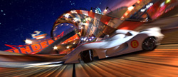 A white race car with the number 6 speeds past a blurred amusement park under a starry night sky.