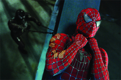 Spider-Man in a red suit looks distressed while a dark figure approaches in the background.